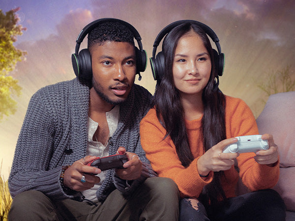 Two people playing video games outdoors with a scenic background